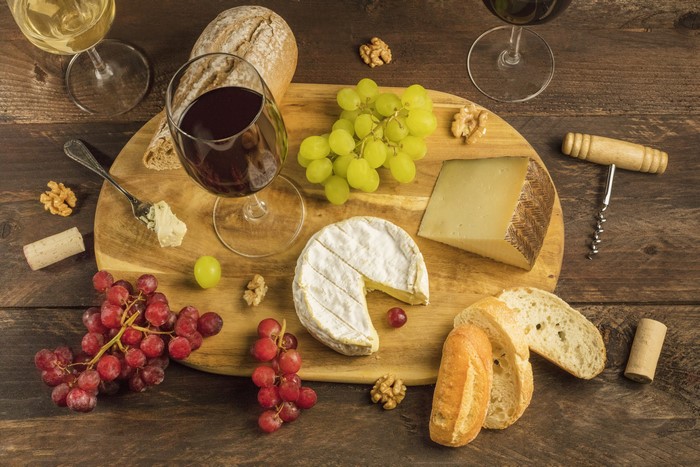 Cheese, Grapes, Bread, and Wine on a Cutting Board