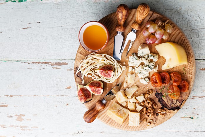 Cheese board with figs, grapes, dried fruit, nuts, and honey