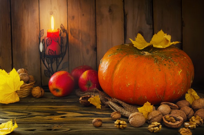 Autumn still life with pumpkin, apples, nuts, and candle