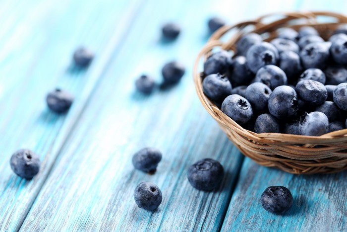 Blueberries in a basket on a blue wooden table