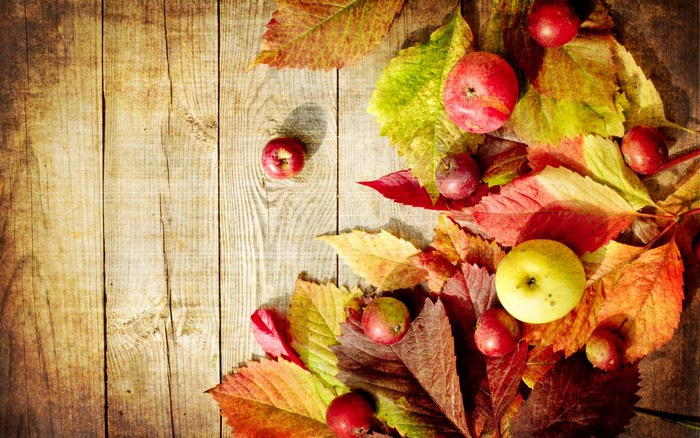 Autumn leaves and apples on wood planks