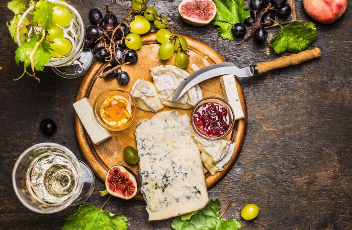 Cheese, Grapes, Figs, Jam, and Wine on a Cutting Board