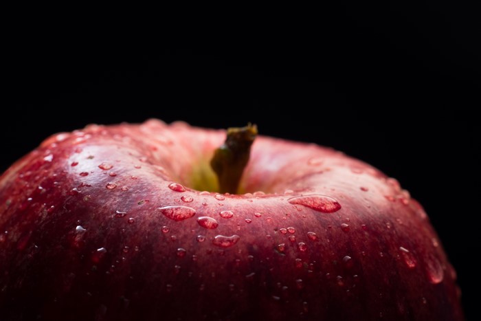 Close-up of a red apple with water drops on a black background