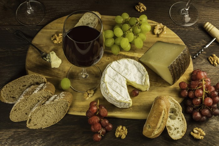 Wine, Cheese, Grapes, Nuts, and Bread on a Cutting Board