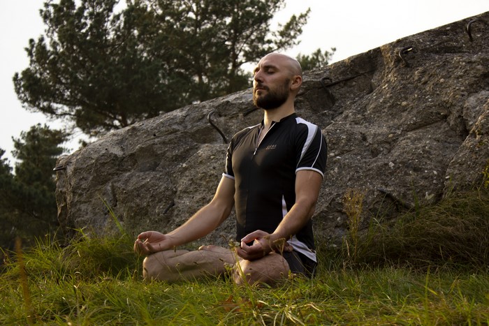 Bald Man Meditating in Lotus Position on Grass
