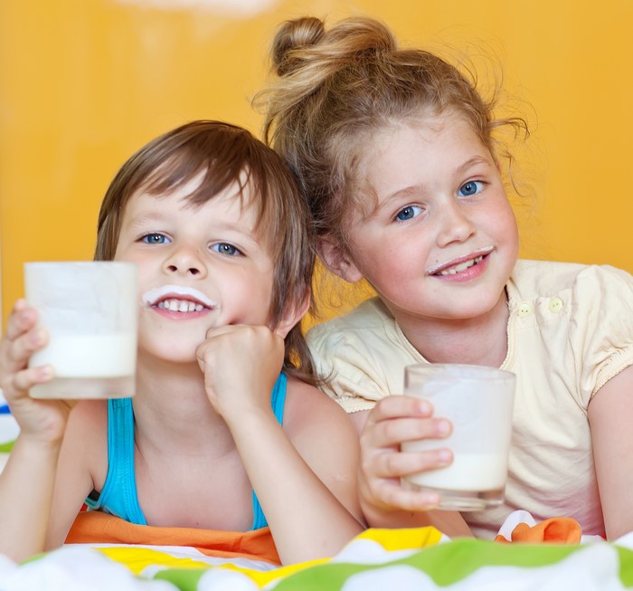 Two children with milk mustaches holding glasses of milk
