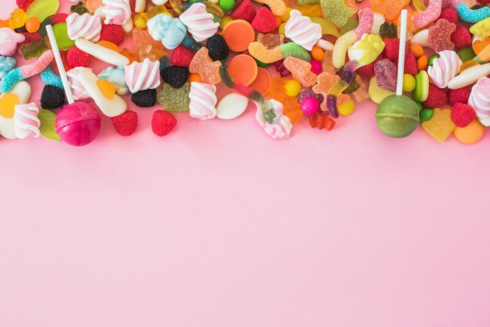 Assortment of colorful candies and lollipops on a pink background
