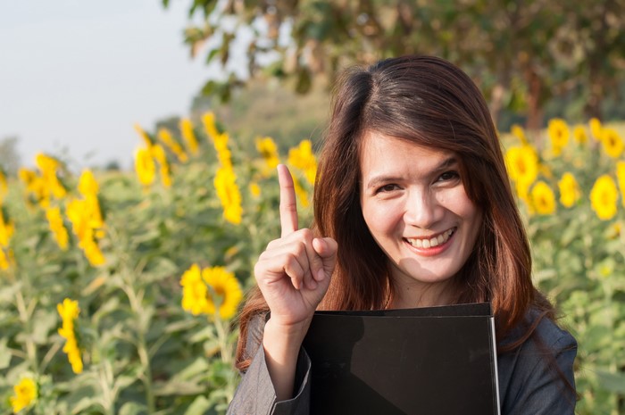 Woman in a sunflower field holding a folder
