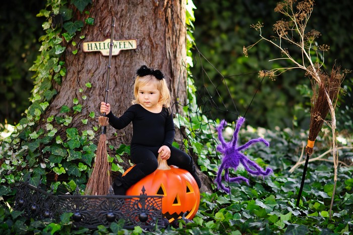 Girl in Halloween costume sitting on a pumpkin