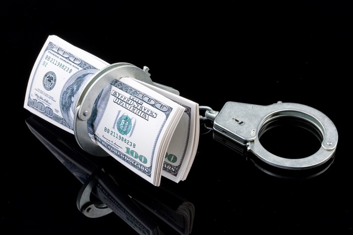 Handcuffs on a roll of US Dollar banknotes