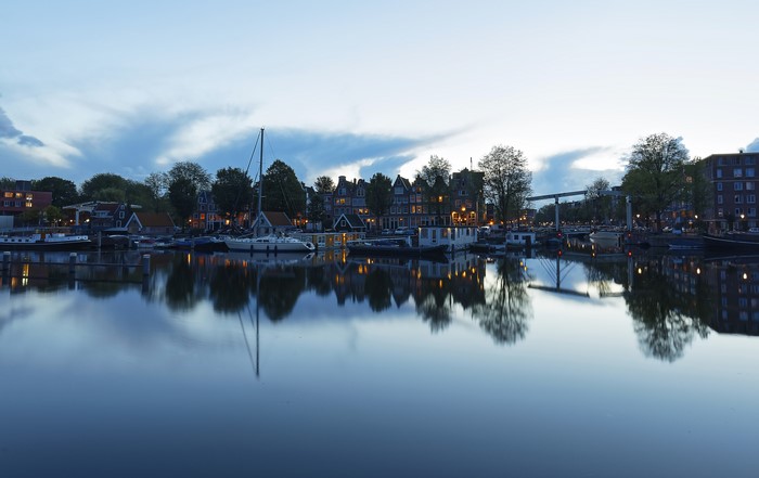 Amsterdam canal with boats and houses at dusk