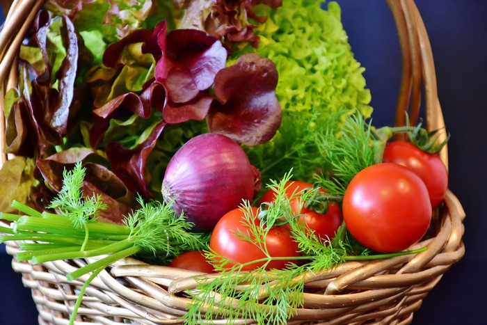 Vegetables in a wicker basket with dill, onion, and tomatoes