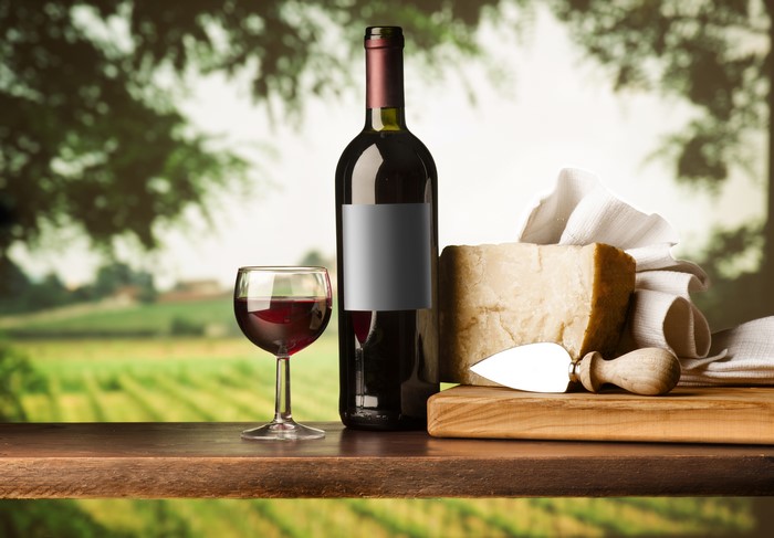 Wine bottle, glass, cheese, and knife on a table