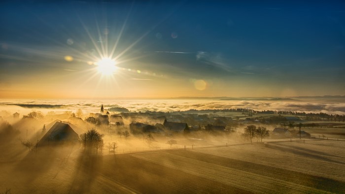 Sunrise over a foggy village with sun rays