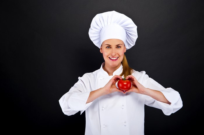 Chef holding a tomato with hands in heart shape