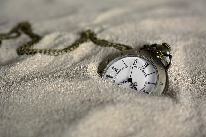 Pocket watch buried in sand
