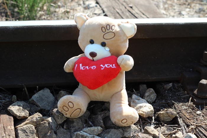 Teddy bear with heart on train tracks