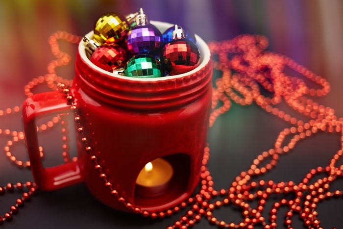 Christmas ornaments in a red mug with a candle
