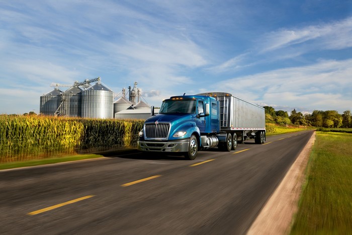 Blue International Truck driving on a road with silos