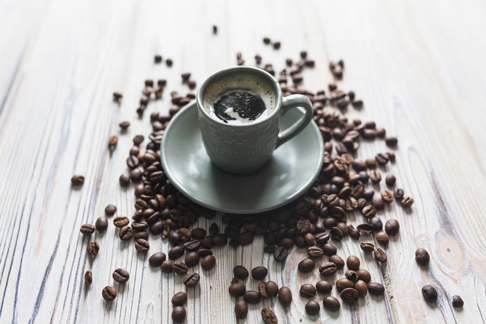 Coffee cup and saucer surrounded by coffee beans