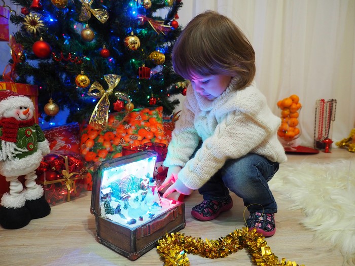 Little girl with Christmas tree and gifts