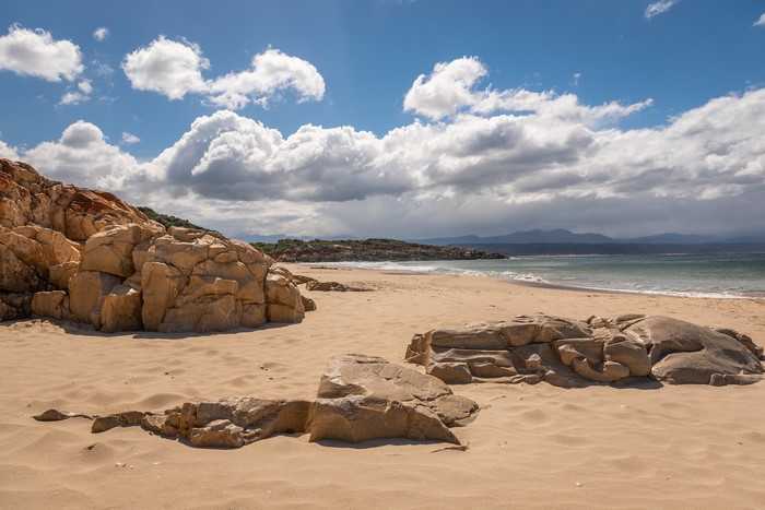 Sandy beach with large rocks and cloudy sky