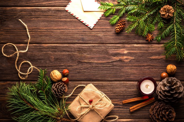 Christmas gift, pine cones, nuts, candle, and envelope on wood