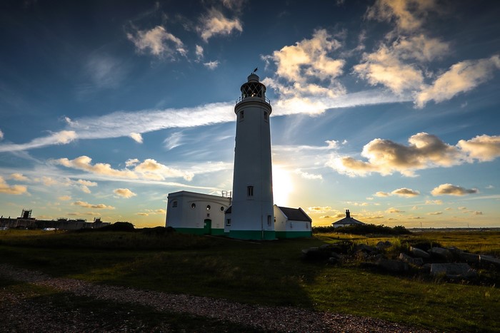 White lighthouse at sunset with dramatic clouds