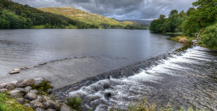 River with a small waterfall and wooded hills in England