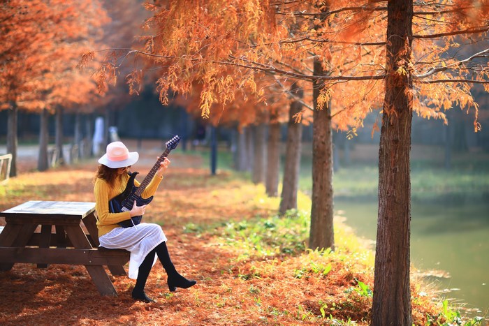 Woman playing guitar in autumn park
