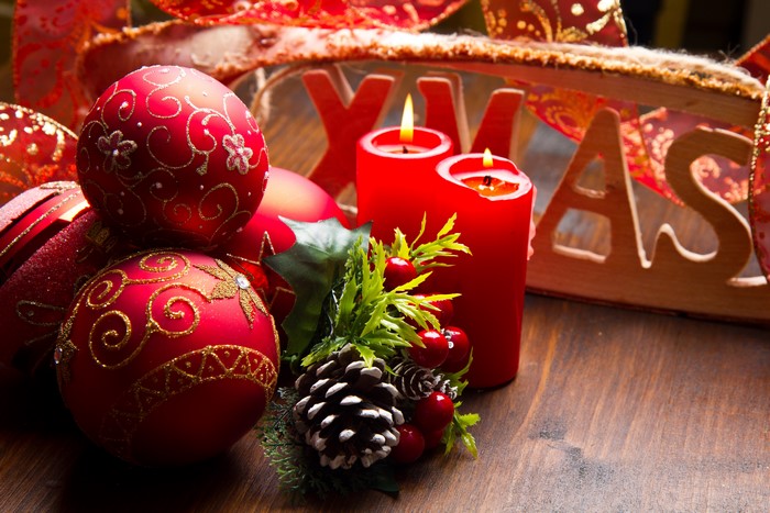 Christmas ornaments, candles, and pine cone on wooden table