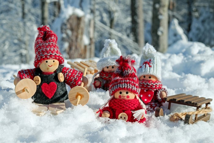 Four dolls in winter hats and scarves in the snow