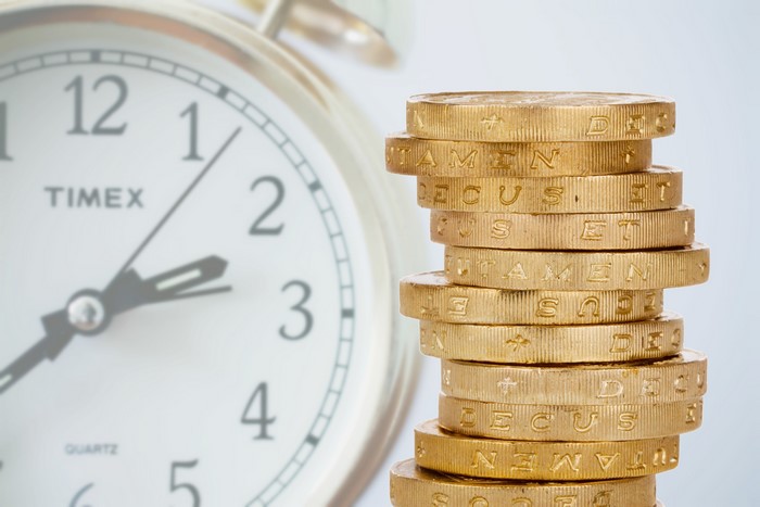 Stack of Coins next to Timex Quartz Clock