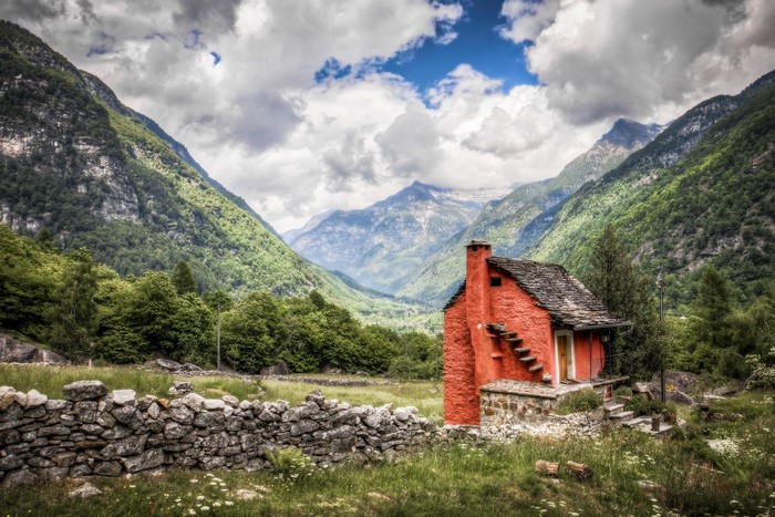 Red house in a mountain valley with stone wall