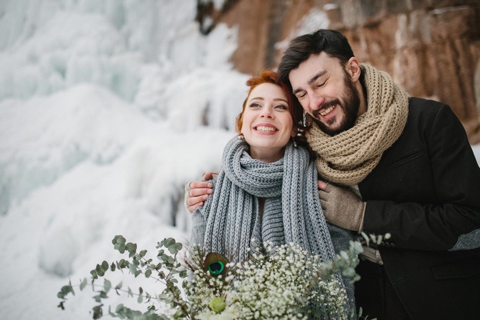 Couple hugging in winter with frozen waterfall