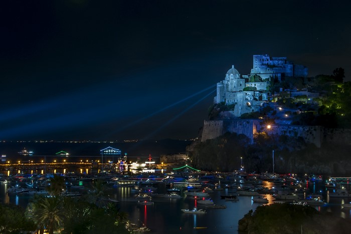 Castello Aragonese at night with a harbor full of boats