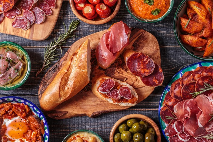 Tapas spread with bread, cured meats, olives, and dips