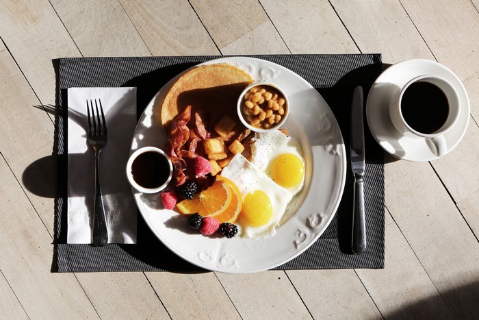 Breakfast with fried eggs, bacon, pancakes, and coffee