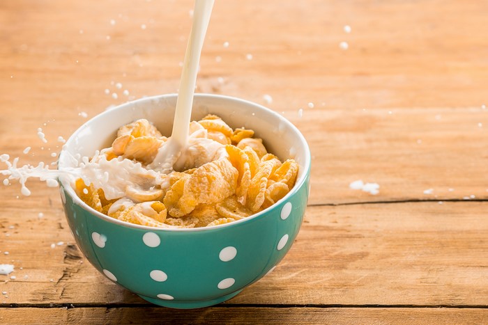 Milk Pouring into Cereal Bowl on Wooden Table