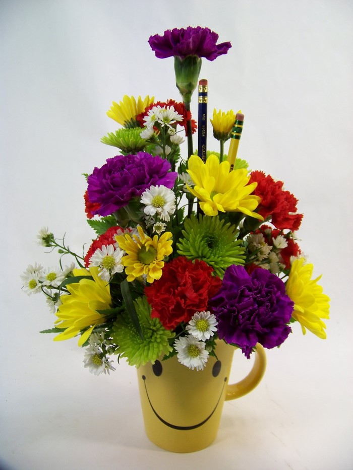 Flower arrangement in a smiley face mug with pencils