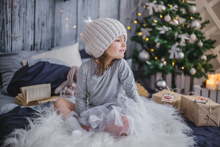 Little girl in winter hat with Christmas gifts