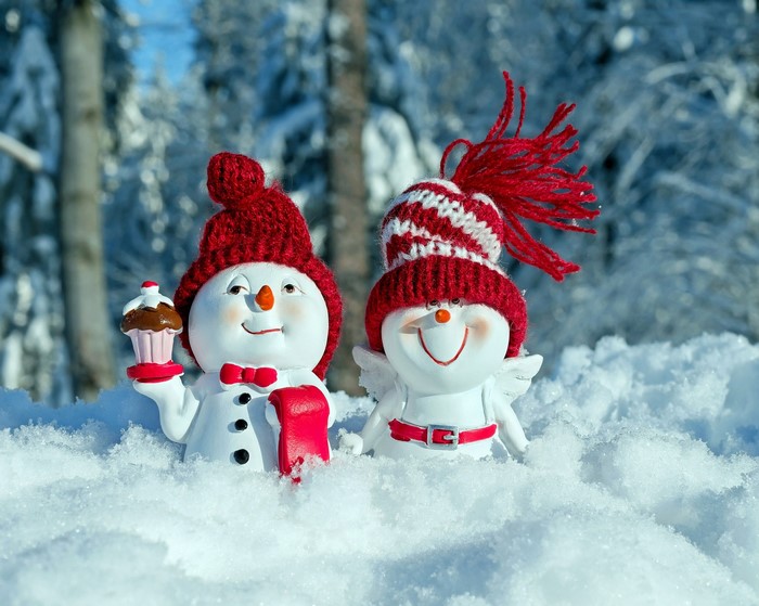 Two snowmen in winter hats with a cupcake