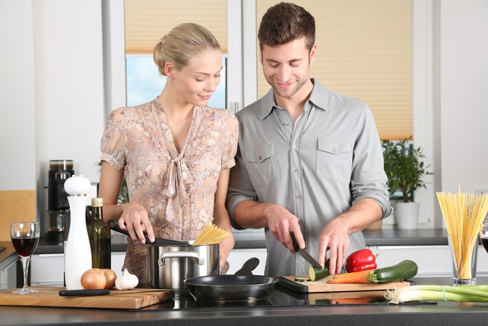 Couple cooking pasta and vegetables in a kitchen