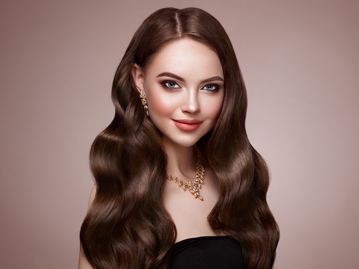 Woman with brown wavy hair and jewelry