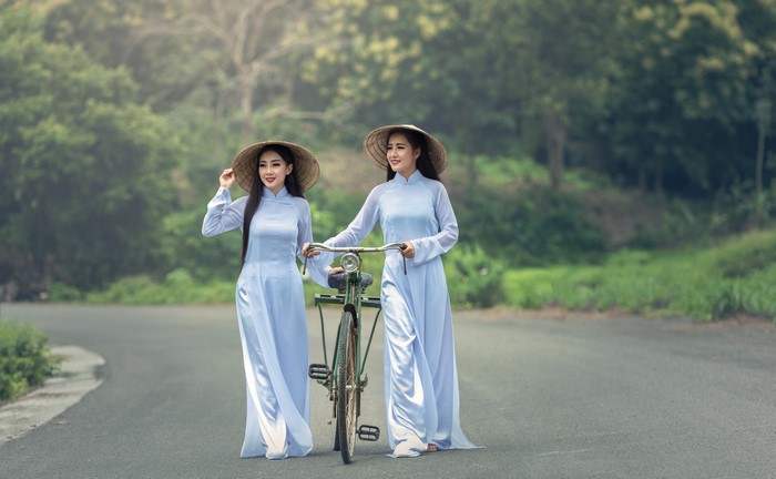 Two Women in Traditional Dress Walking with Bicycle