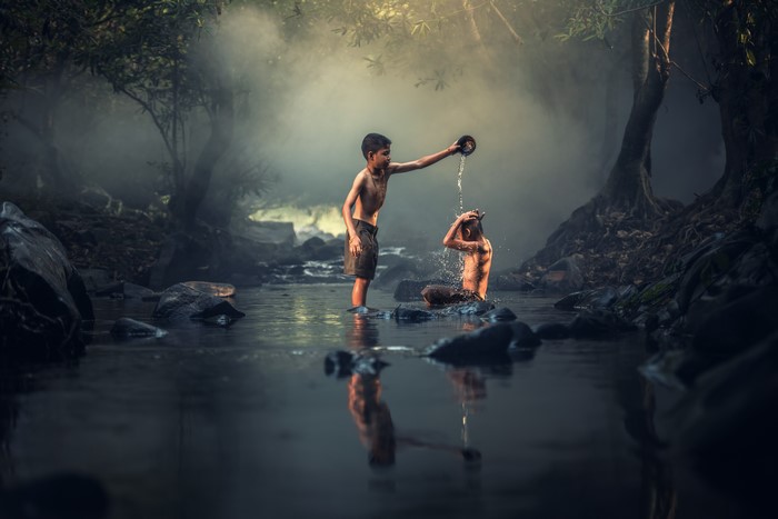 Two Asian boys bathing in a stream