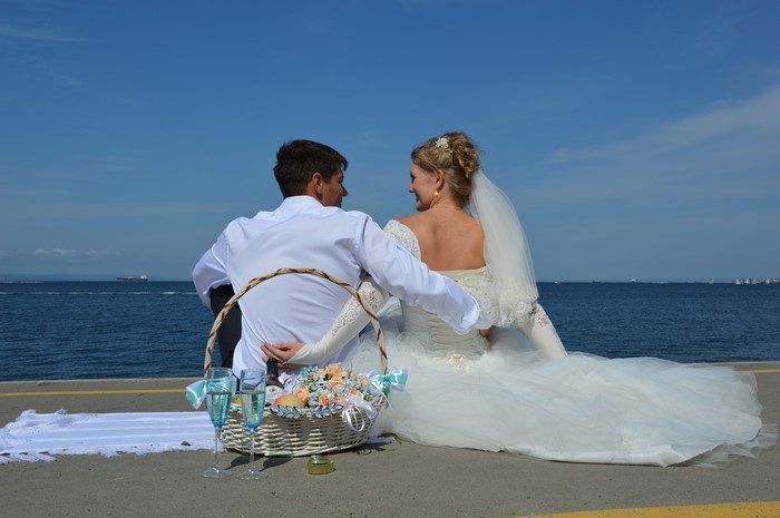 Bride and Groom Sitting by the Sea with Champagne