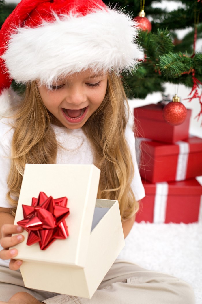 Girl in Santa hat opening a Christmas gift