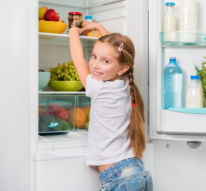 Girl reaching into a refrigerator