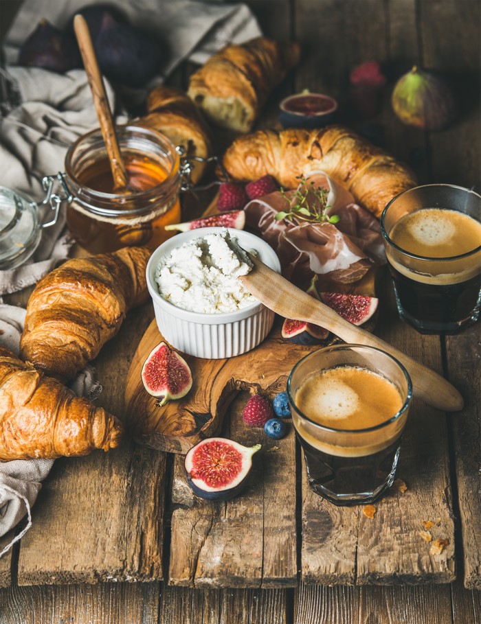 Breakfast spread with croissants, cheese, figs, and coffee